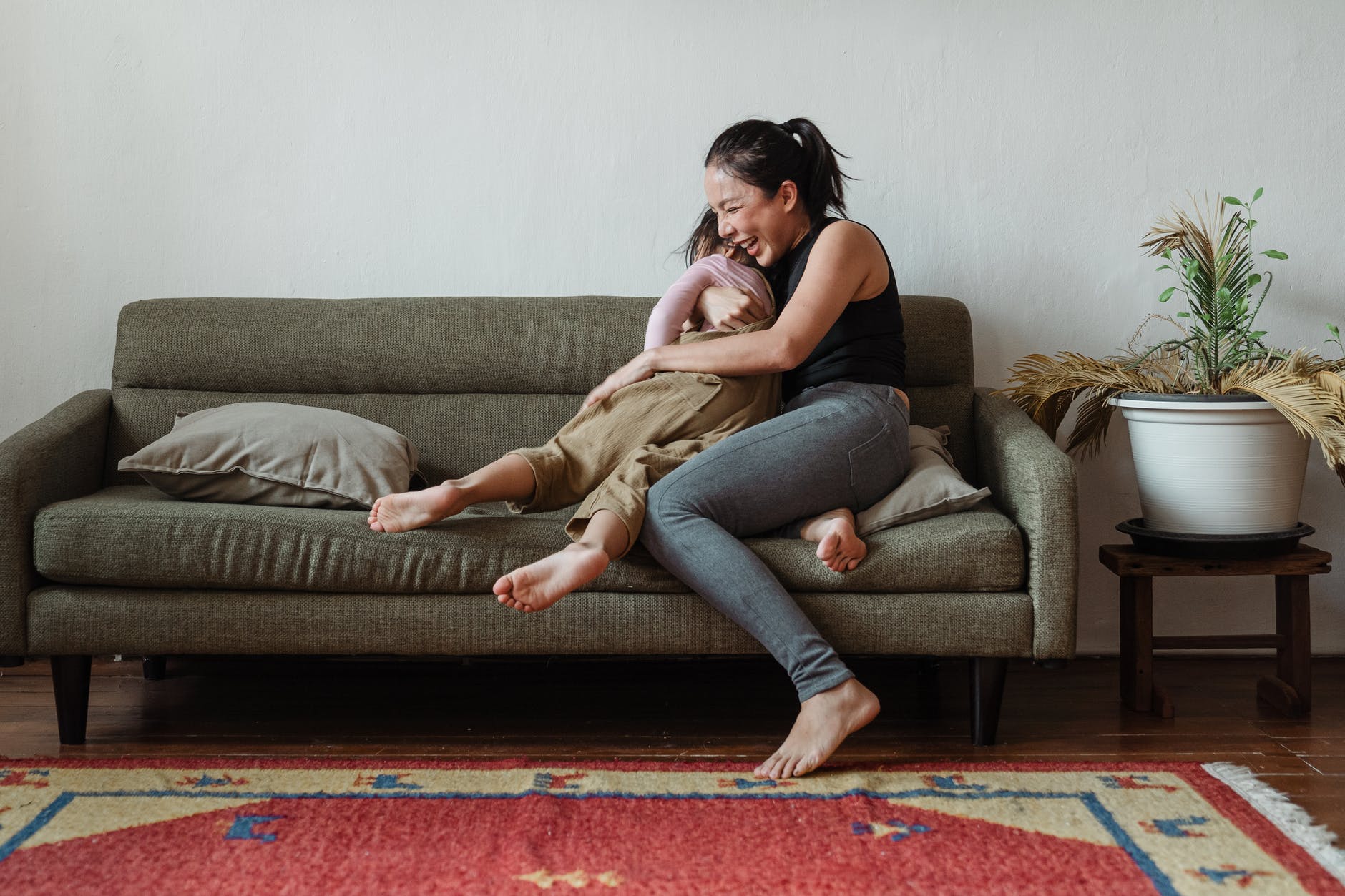 photo of woman sitting on couch while hugging her child